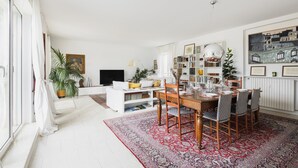 A spacious living room with a dining area, white walls, and a large window. - Easylife - 230sqm attic with terrace Bocconi area (Milano)