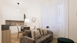 A modern living room with a sofa, a coffee table, and a dining area with a kitchen in the background. - Easylife - Oasis of style 10min from Duomo (Milano)