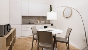 A modern kitchen with white cabinets, a marble countertop, and a round mirror. There is a dining table with four chairs and a floor lamp. - Easylife - Oasis of style 10min from Duomo (Milano)