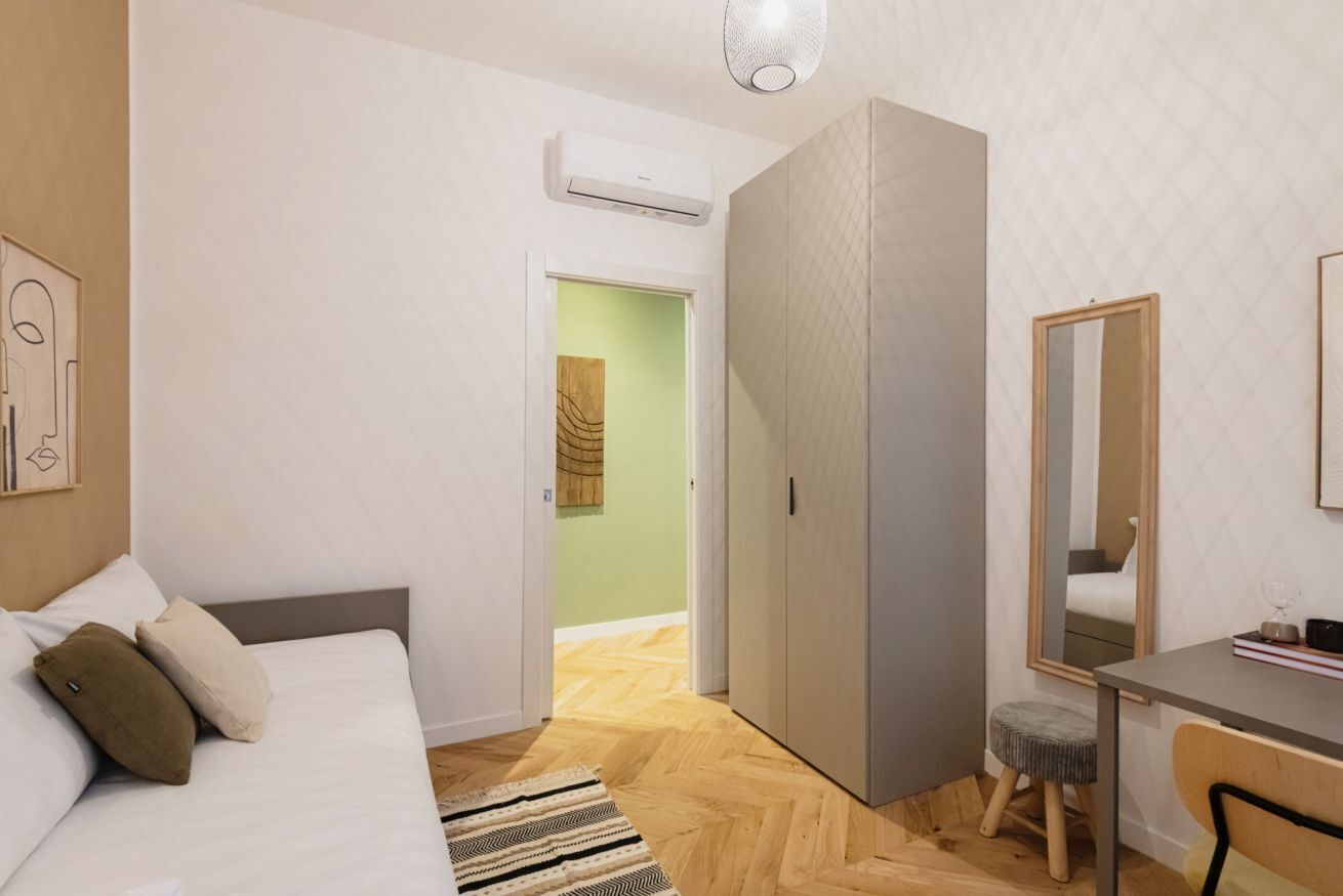 Un dormitorio con cama, mesita de noche y escritorio con silla.