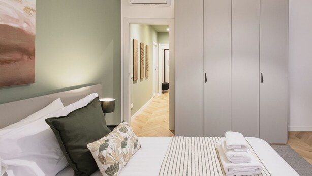 A bedroom with a bed, pillows, a bedside table, a wardrobe, and a hallway leading to another room. - Easylife - Oasis of style 10min from Duomo (Milano)
