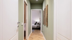 A hallway with a wooden herringbone floor, light green walls, and white doors. - Easylife - Oasis of style 10min from Duomo (Milano)