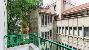 Ein mehrstöckiges Gebäude mit einem Balkon und einem grünen Metallgeländer.