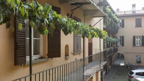 A building with a balcony, a car parked in the courtyard, and a vine-covered wall. - Easylife - Naviglio, sweet dreams in the heart of the fun (Milano)