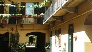 A courtyard with a central archway, potted plants, and a staircase leading to an upper level.