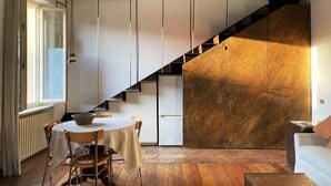 A modern interior with a wooden staircase, a dining area with a table and chairs, and a white sofa.
