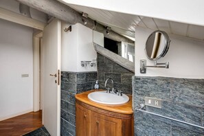 Un baño con tocador de madera, lavamanos blanco y espejo.