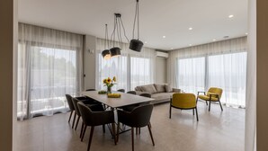 A modern living room with a dining area, large windows, and a sofa. - Villa Luce by Villas Guide (Pijavicino)