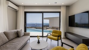 A modern living room with a sofa, a yellow armchair, a coffee table, and a TV. A large window offers a view of a pool and the sea. - Villa Luce by Villas Guide (Pijavicino)