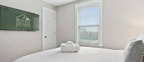 Habitación de hotel con cama, ventilador de techo, ventana con persianas y un cartel en la pared.