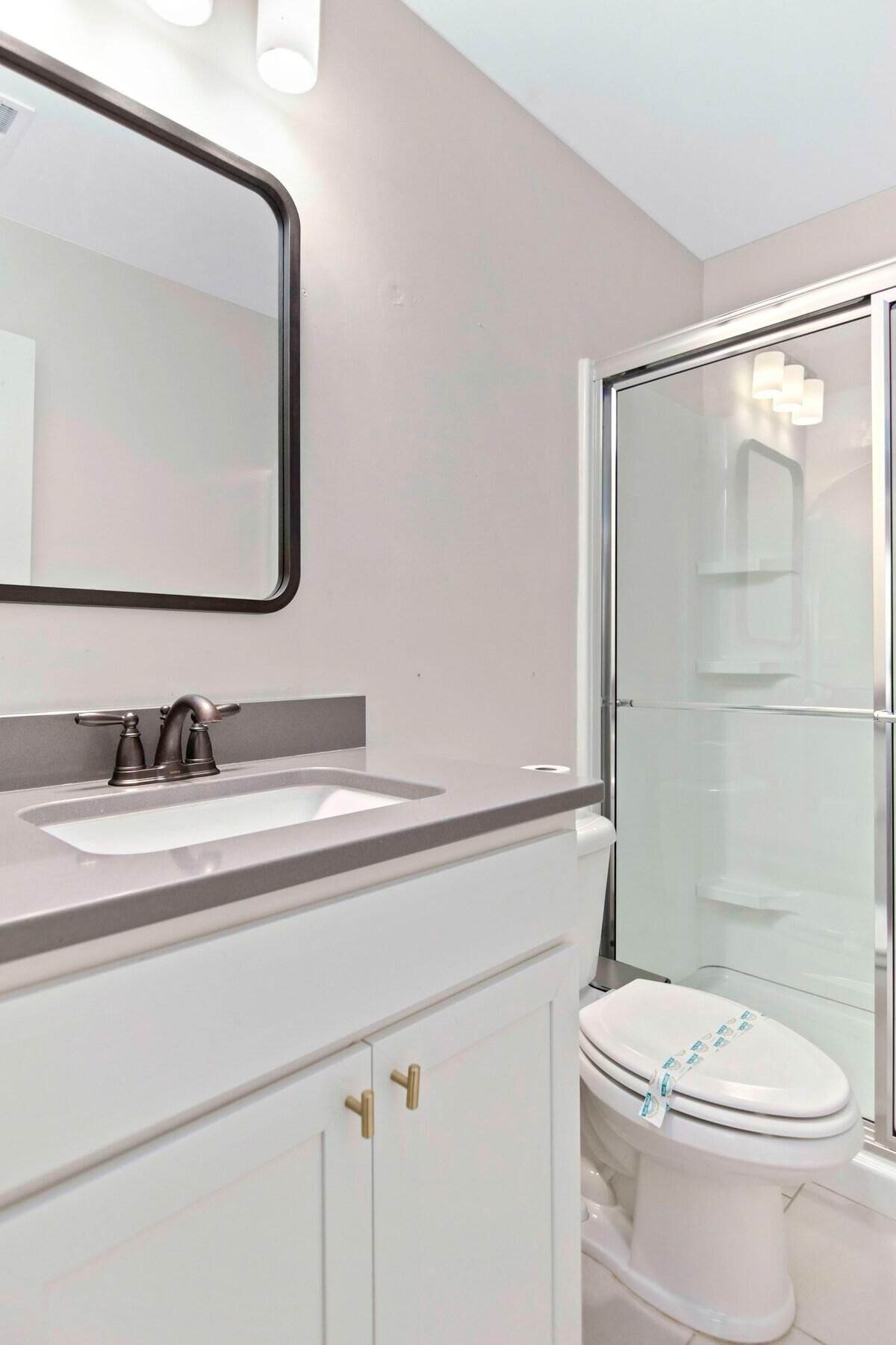 A modern bathroom with a white sink, a mirror, and a toilet.