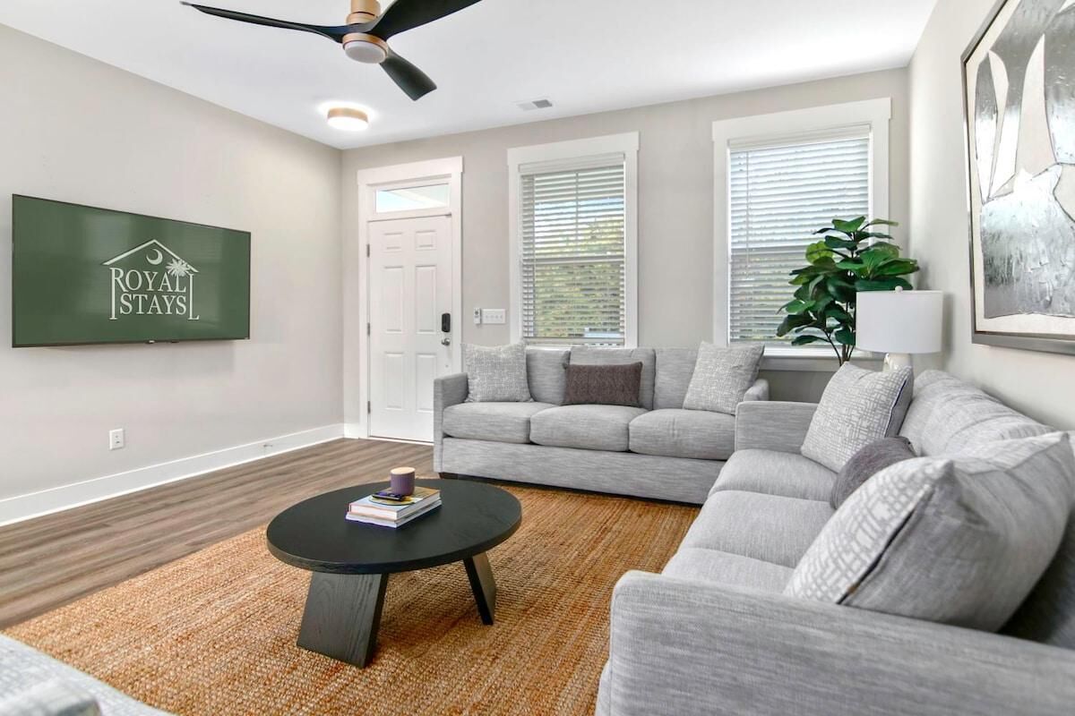 A modern living room with a grey sectional sofa, a round black coffee table, and a ceiling fan.