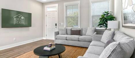 A modern living room with a grey sectional sofa, a round black coffee table, and a ceiling fan.