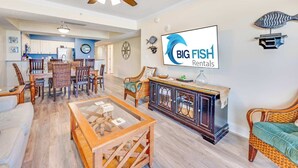 Un salón amplio con zona de comedor, una cocina al fondo y un cartel de BIG FISH Rentals.