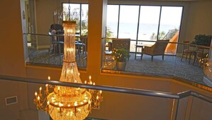 A hotel lobby with a large chandelier, seating areas, and a view of the ocean. - New Coastal Charm, Direct Oceanfront Views, Pools! (Myrtle Beach)