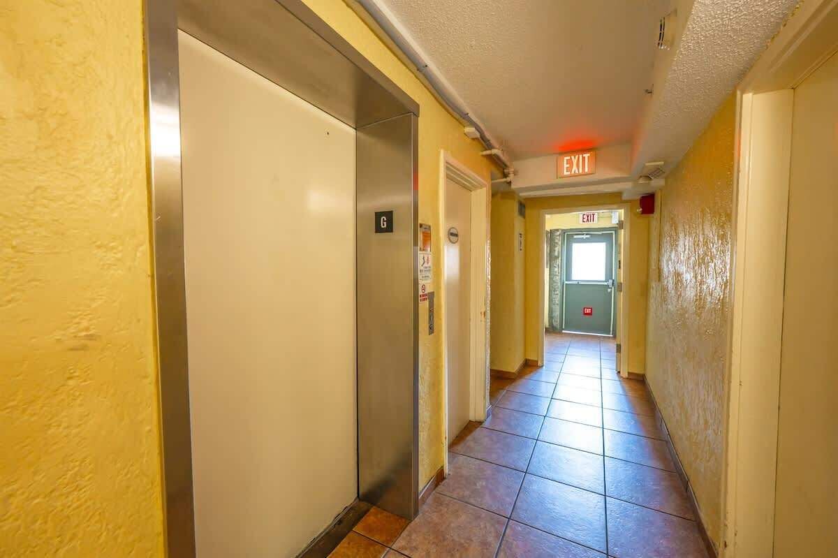 A hallway with an elevator, exit signs, and a door marked with a 'G'.