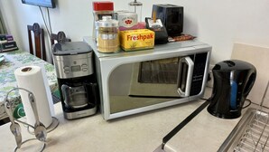 A kitchen with a microwave, coffee maker, and a toaster.