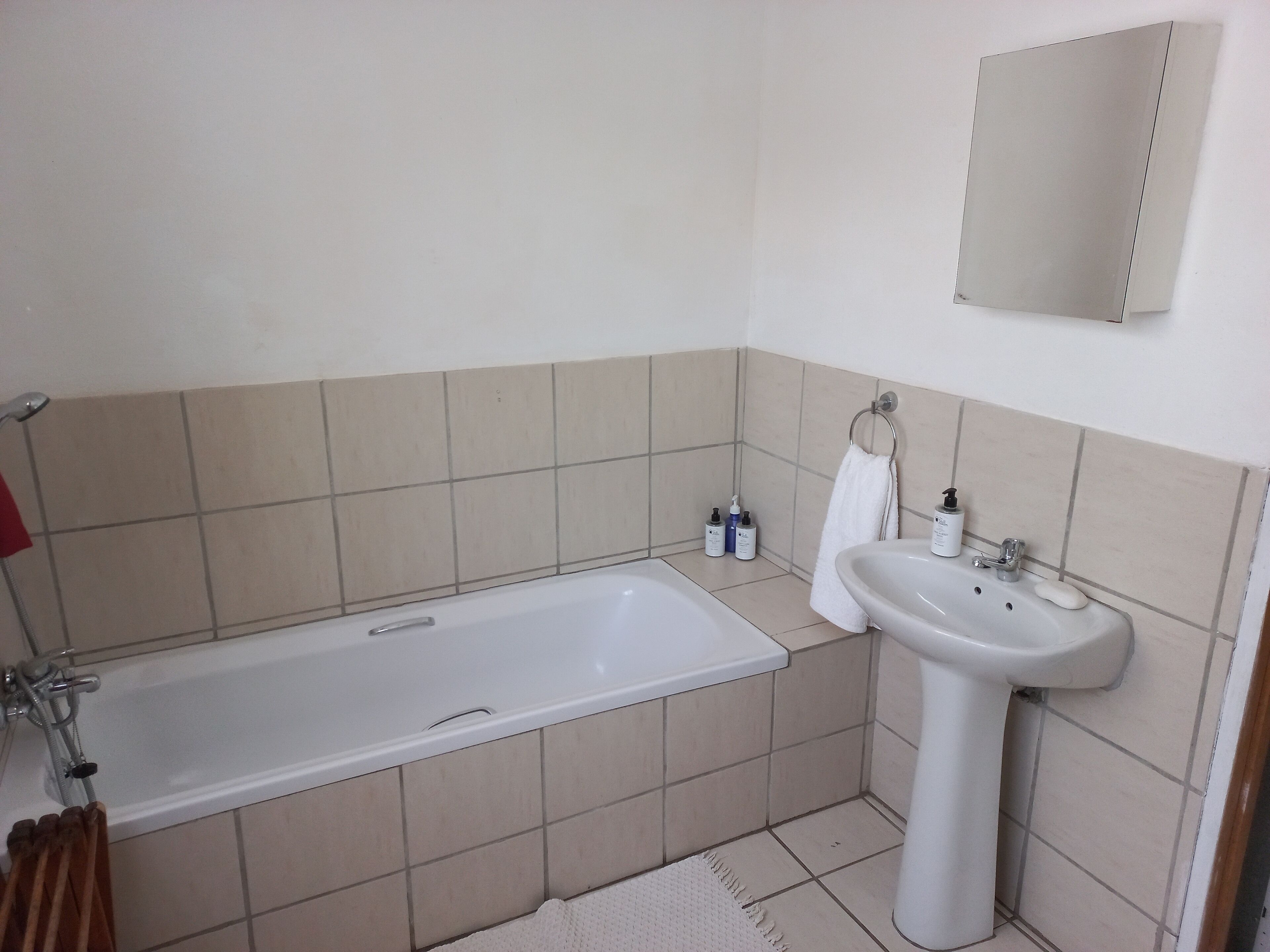 Een badkamer met een bad, een wastafel en een spiegel.