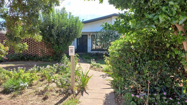 A pathway leading to a building with a number sign '55' indicating a property or unit number.