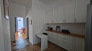 A modern kitchen with white cabinets, a wooden countertop, and a dining area with a table and chairs. - APPT F2 RDJ 4/5 PERSONS- ALL COMFORT - QUIET - CLOSE TO THERMAL BATHS  (La Bourboule)