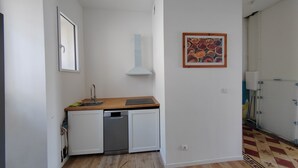 A compact kitchen with white cabinets, a stainless steel dishwasher, and a wooden countertop. - APPT F2 RDJ 4/5 PERSONS- ALL COMFORT - QUIET - CLOSE TO THERMAL BATHS  (La Bourboule)
