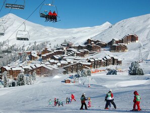 En skidort med flera byggnader i chaletstil, skidliftar och ett snötäckt landskap.