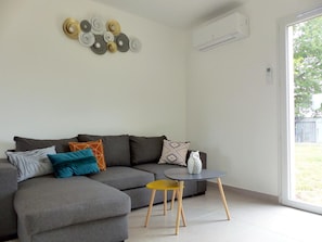 A modern living room with a grey sectional sofa, a small round table with a yellow chair, and a decorative wall piece.