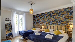 A room with two beds, a mirror, and a patterned wall.