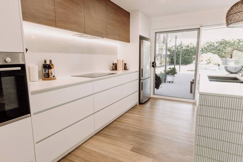 Een moderne keuken met witte kasten, een inbouwoven en een roestvrijstalen koelkast.