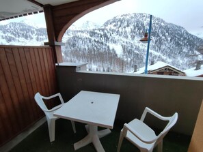 A balcony with a table and two chairs, overlooking a snowy mountain landscape. - Charming 2-room apartment in Isola 2000 close to slopes (Isola 2000)