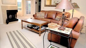 A living room with a leather sofa, a coffee table, a lamp, and a fireplace. - CV 8245  Cozy Condo at the Base of the Mountains (Tucson)