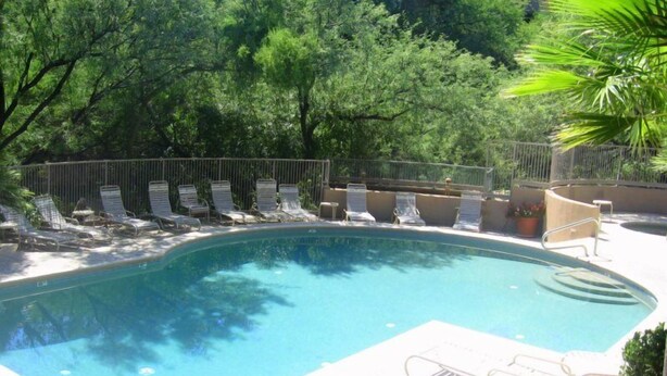 A swimming pool with lounge chairs and a fence. - CV 8245  Cozy Condo at the Base of the Mountains (Tucson)