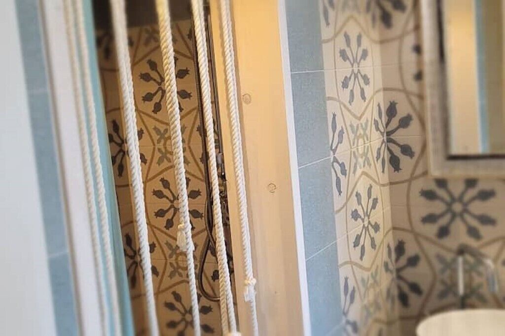 Een badkamer met patroontegels en een zichtbare douchegordijnrail.