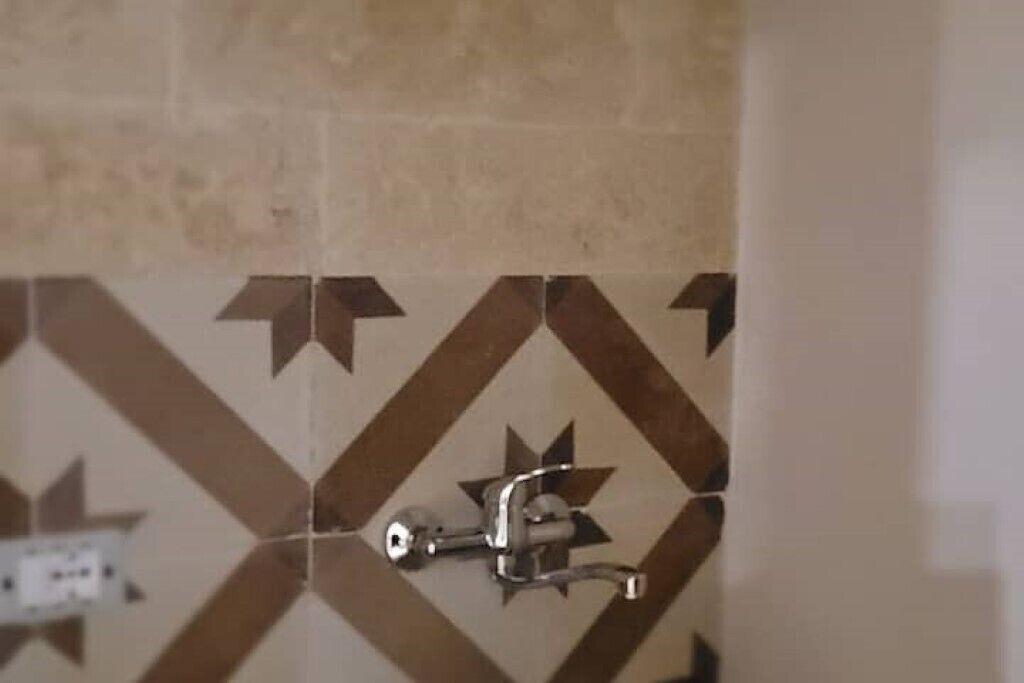 Een betegelde badkamerwand met een geometrisch patroon.