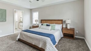 A bedroom with a bed, nightstands, a ceiling fan, and a door leading to another room. - Charming 3BR Farmhouse • Fenced Acre • Madison (Madison)