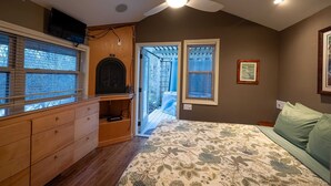 A bedroom with a bed, wooden dresser, ceiling fan, and a door leading to a balcony. - Hot Tub, Fire Pit, Secluded, 5 Minutes Eureka (Eureka Springs)