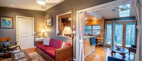 A cozy living room with a red sofa, wooden coffee table, and a ceiling fan.