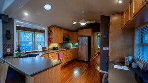 A modern kitchen with wooden cabinets, stainless steel appliances, and a central island. - Hot Tub, Fire Pit, Secluded, 5 Minutes Eureka (Eureka Springs)