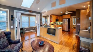 A modern kitchen with a central island, built-in appliances, and a dining area with a sofa and table. - Hot Tub, Fire Pit, Secluded, 5 Minutes Eureka (Eureka Springs)