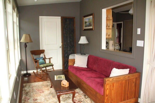 Un salon avec un canapé en bois, un fauteuil à bascule, une table basse et un lampadaire.