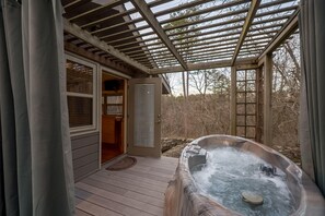 Un bain à remous sous une pergola, une porte en bois et une vue sur les environs.