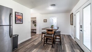 A modern kitchen with a stainless steel refrigerator, a wooden dining table with two chairs, and a cityscape poster on the wall. - Gulfside Getaway Awaits (Corpus Christi)