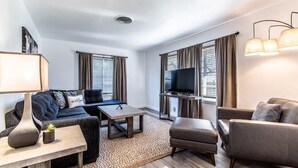 A modern living room with a sofa, armchair, TV, and a coffee table. - Gulfside Getaway Awaits (Corpus Christi)