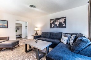 Een moderne woonkamer met een hoekbank, een salontafel en een wereldkaart op de muur.