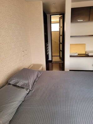 Ein Schlafzimmer mit Bett, Nachttisch, Kleiderschrank und angrenzendem Badezimmer.