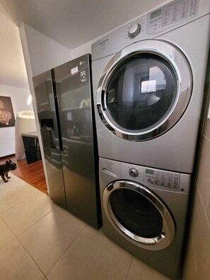 A compact washer and dryer unit in a modern kitchen with a tiled floor.