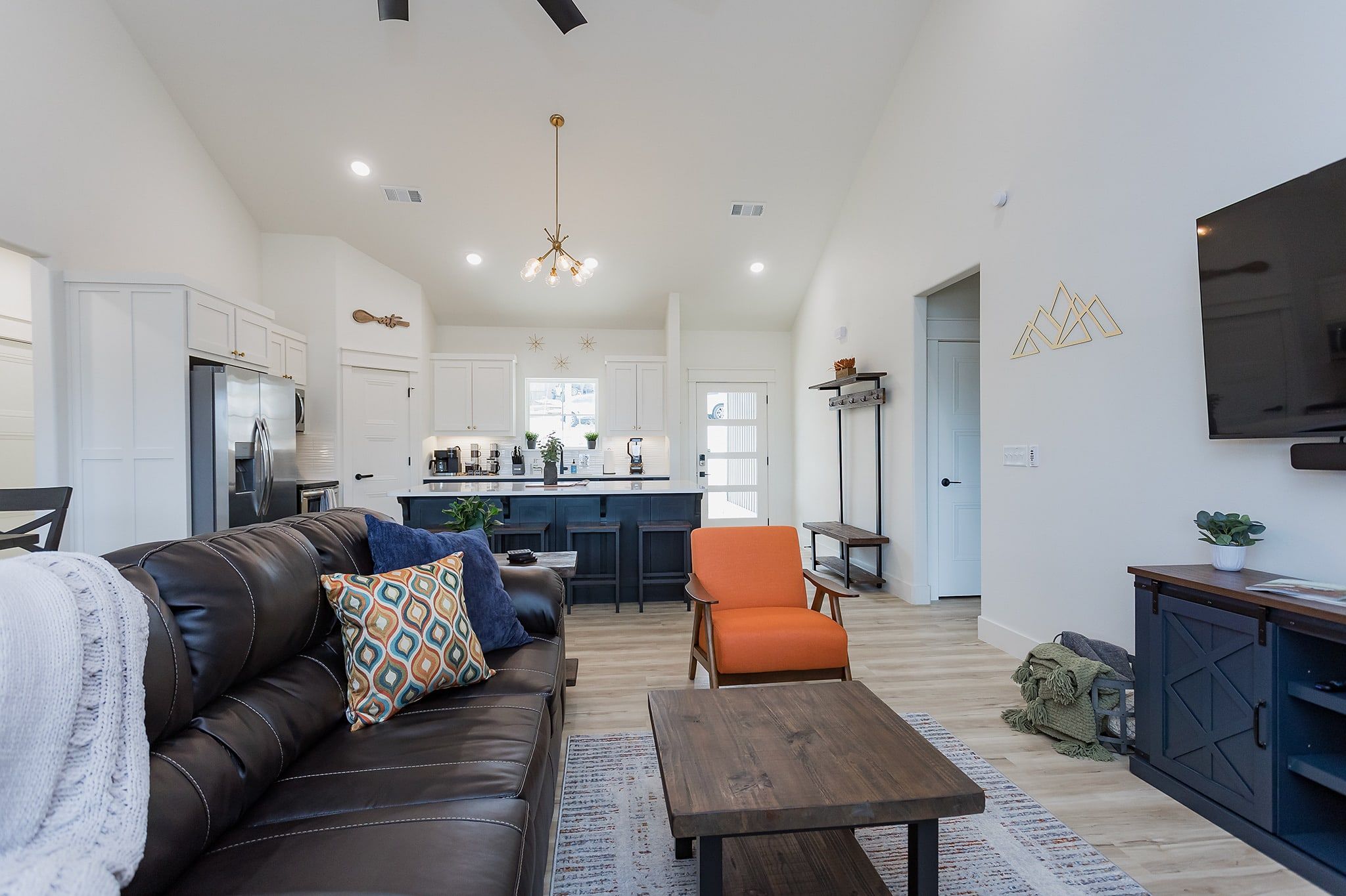 A modern living room with a leather sofa, a wooden coffee table, and a bright kitchen in the background.