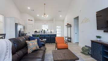 A modern living room with a leather sofa, a wooden coffee table, and a bright kitchen in the background.