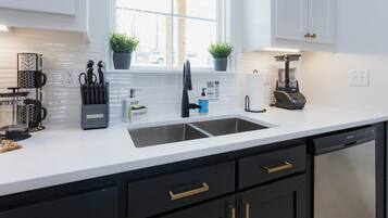 A modern kitchen with a double sink, black cabinets, and a built-in dishwasher.