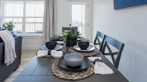 Ein Essbereich mit einem Tisch, gedeckt für vier Personen, inklusive Schalen, Tellern und einem Blumentopf.